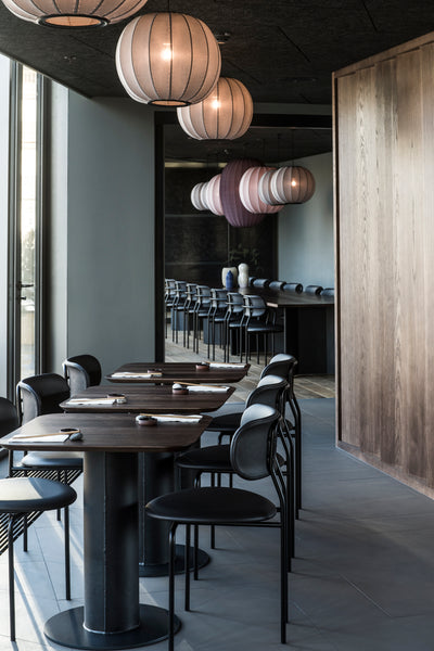 Modern restaurant interior with tables, chairs, and decorative lighting.