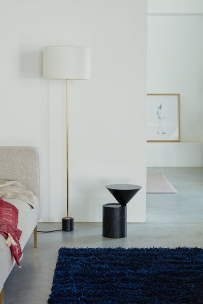 Modern interior with a floor lamp, side table, and blue rug.