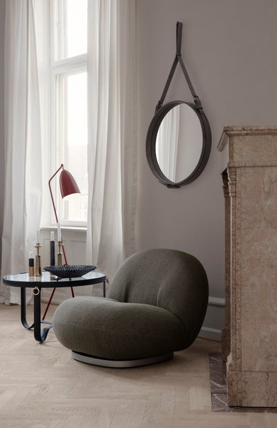 Modern interior with a gray chair, round mirror, and side table.