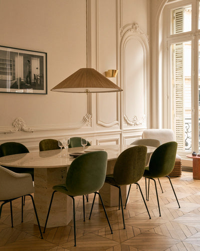 Dining room with marble table and green chairs in a stylishly decorated room.