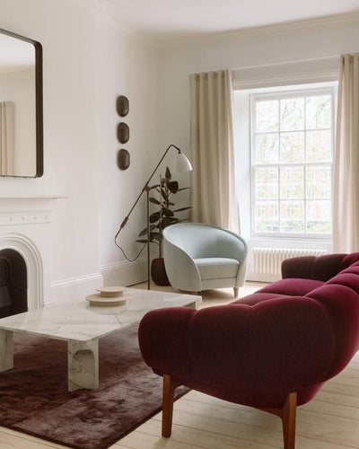 Modern living room with a red sofa, white armchair, and marble coffee table.