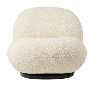 A modern, rounded boucle armchair in cream-colored textured fabric, featuring a black circular base, shown against a plain white background.
