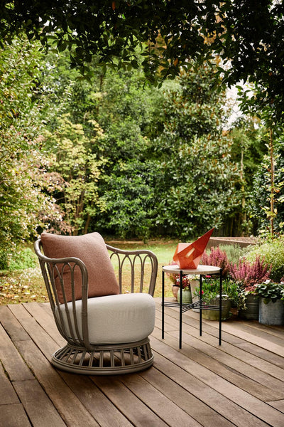 Chair with a cushion on a wooden deck surrounded by greenery