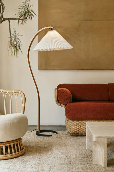 Modern living room with a floor lamp, red sofa, and wicker chair.