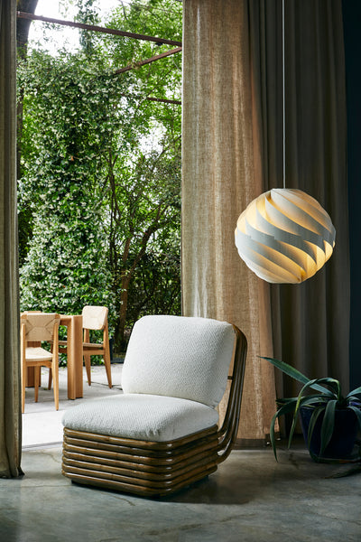 Modern chair with a textured white cushion in a room with curtains and outdoor view