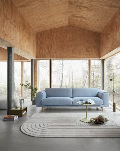 Modern living room with a blue sofa, wooden floor, and large windows.