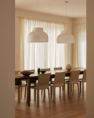Dining room with a wooden table and chairs under two pendant lights.